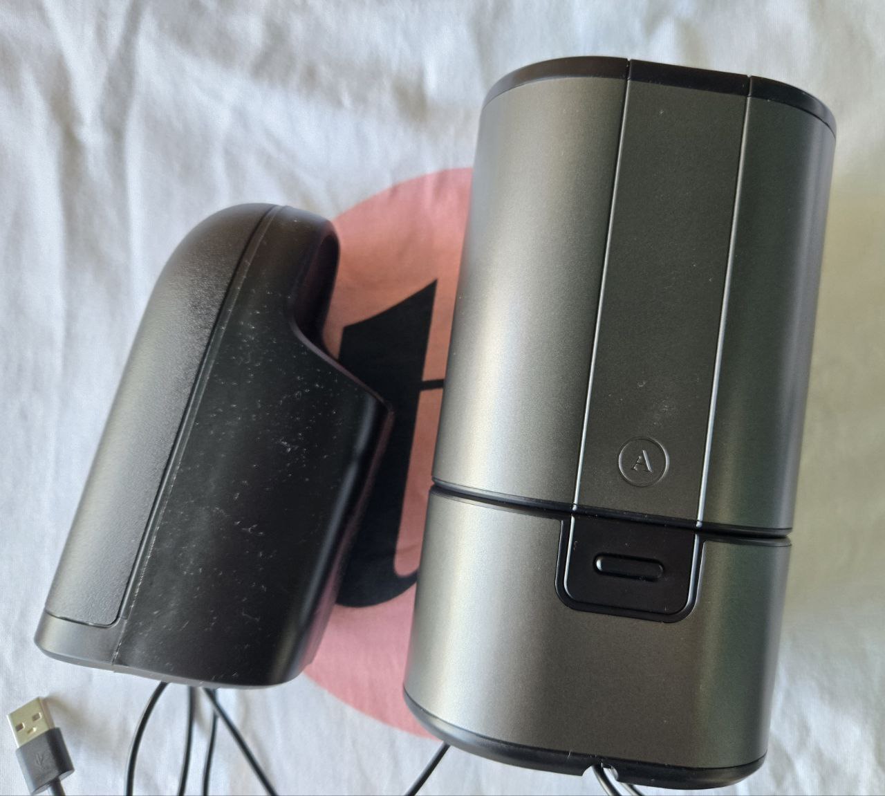 Arcwave Ion and its DryTech charging base laid side by side with USB cable attached for charging
