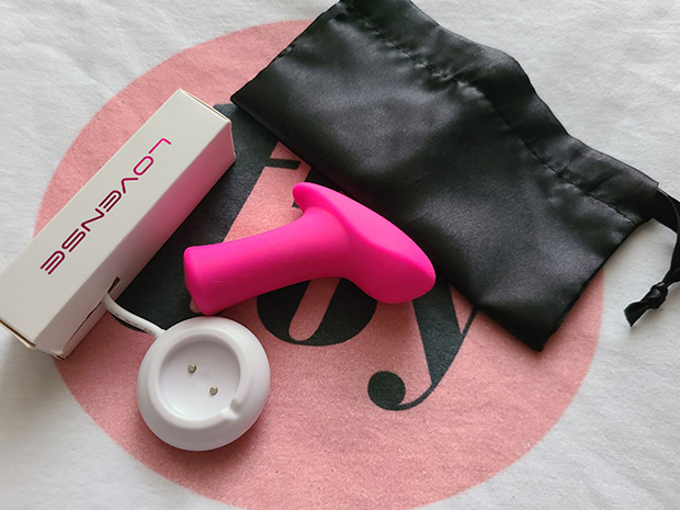 Lovense AMbi next to its charger and pouch.