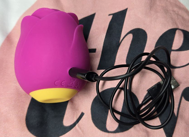 ROMP Rose connected to its magnetic charging cable, photographed during real-life charging setup by the tester