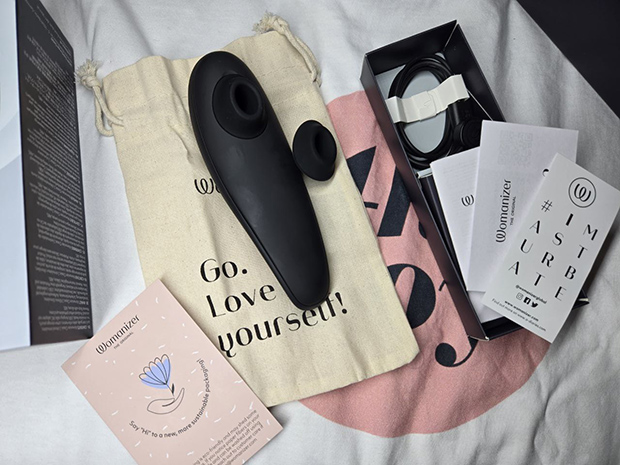 Full flat-lay of the Womanizer Classic 2 packaging and contents including toy, extra nozzle, charger, pouch, and manuals—photographed after real-life unboxing.