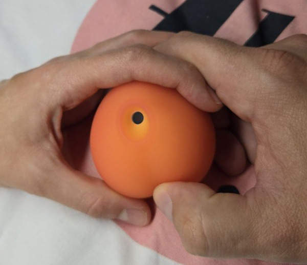 Artistic representation of Womanizer Peach held between hands suggesting partner use during intimate moments