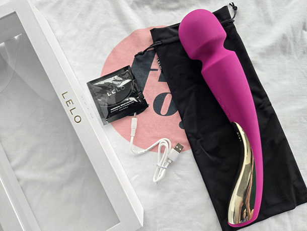 LELO Smart Wand 2 and its accessories - satin bag, usb charging cable, a package of lube, starting guide and warranty card.