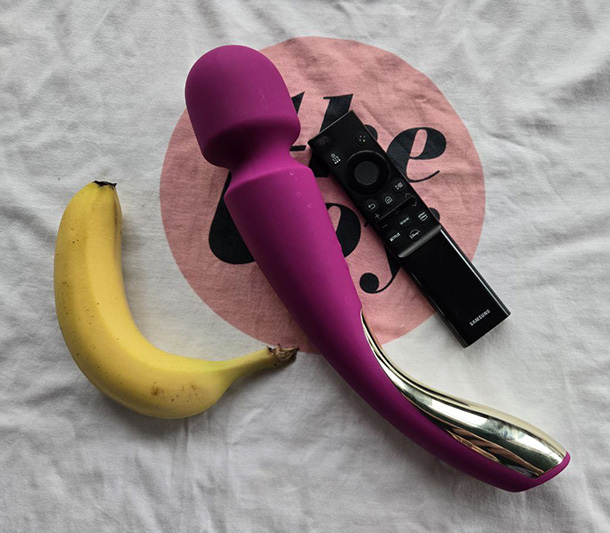 LELO Smart Wand 2 next to a banana and a tv remote for comparison.