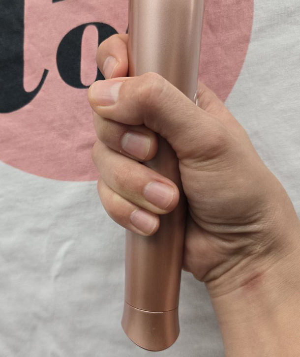 Le Wand Petite wand vibrator held in a hand with smaller fingers, demonstrating how the slim handle allows a full comfortable grip
