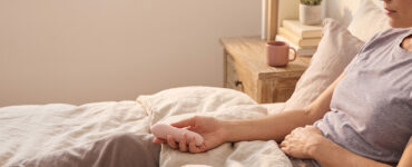 photo of a person reclining on a bed in warm light, suggesting slow-building pleasure that is present but taking time to reach orgasm.