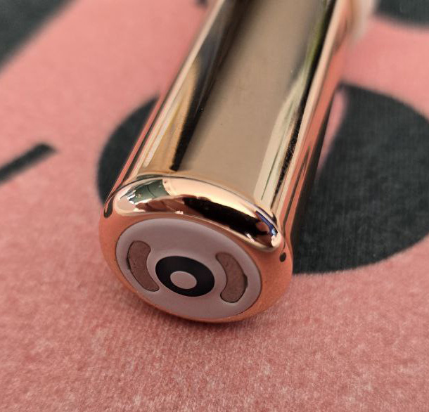 Detail shot showing the Le Wand Bullet's single control button set flush into the polished metal surface, demonstrating how the button sits level with the body of the toy.