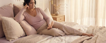 Woman reclining during an intimate moment with subtle visual cues suggesting she is evaluating the experience instead of simply feeling it.