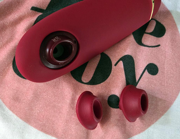 Womanizer Premium 2's two interchangeable silicone nozzle heads — small and medium — shown next to a thumb for size comparison.