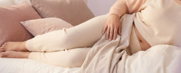photo of a person resting on a bed in warm light, suggesting gentle, buffered exploration when direct touch feels too intense.