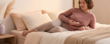 photo of a person alone on a bed in warm light, suggesting the tension of feeling pleasure while also mentally monitoring the experience.