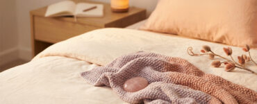 editorial photo of a person alone on a bed in warm light, suggesting early self-consciousness and gentle curiosity during private pleasure exploration