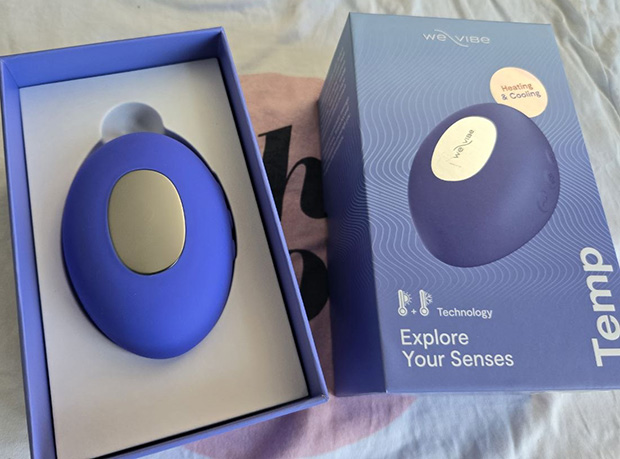 We-Vibe Temp unboxing showing the Lavender Blue vibrator, magnetic USB charging cable, drawstring storage bag, quick-start guide, and safety instructions