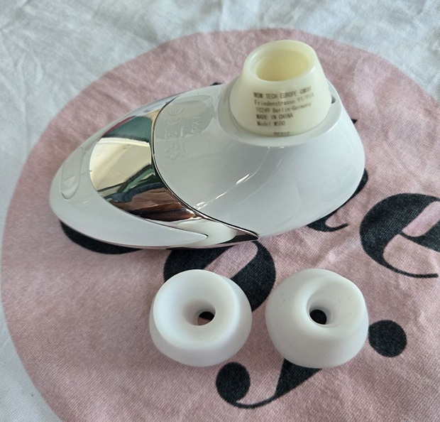 Womanizer w500 with its 2 heads next to it demonstrating the detachable design and size of the mouths